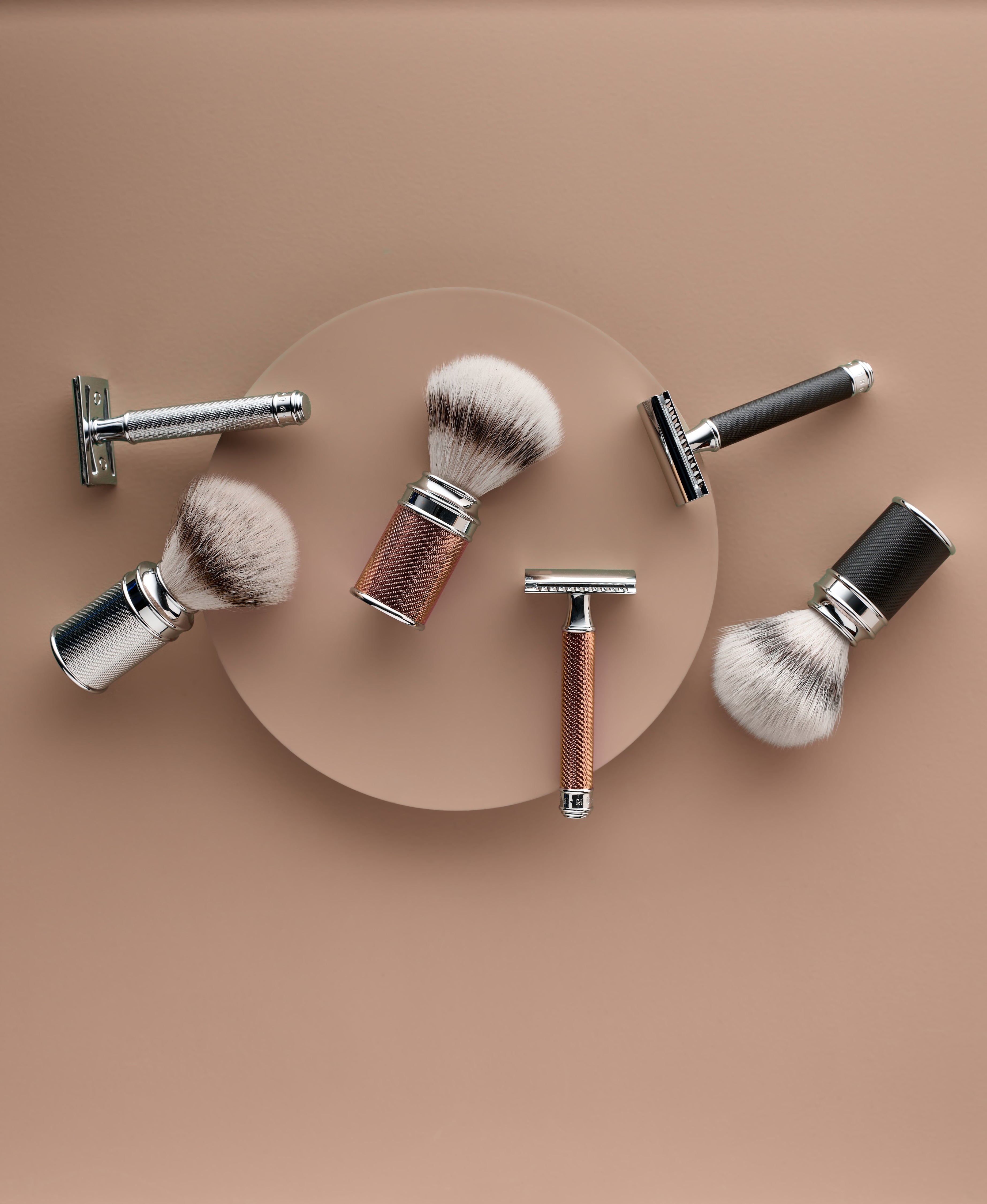 shaving brushes and safety razors with metal handles placed on a beige background.