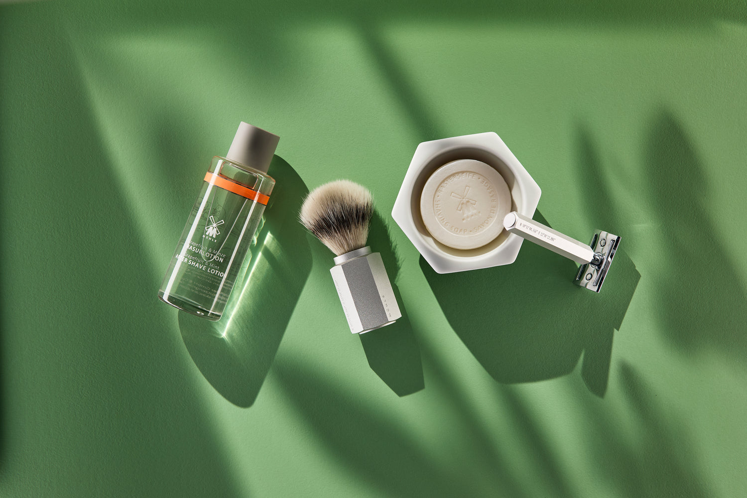 Shaving products including a bottle, brush, and razor on a green background